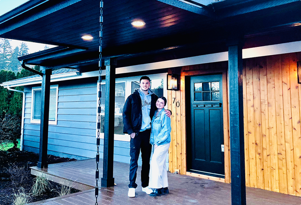 Smiling couple standing outside their new home